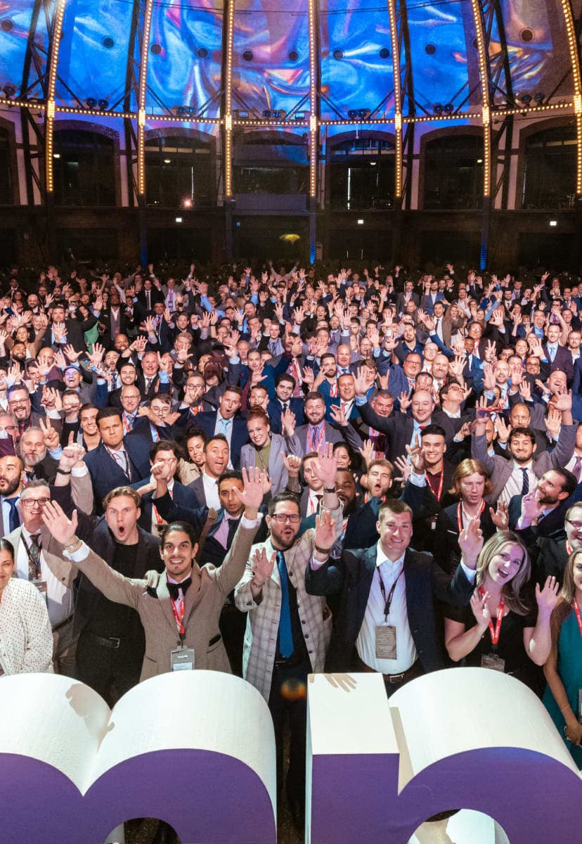 Impact's large team all standing together in one picture, a sea of people in front of large impact sign