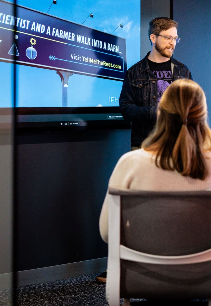 People in a conference room looking at a picture of a billboard on a projection screen