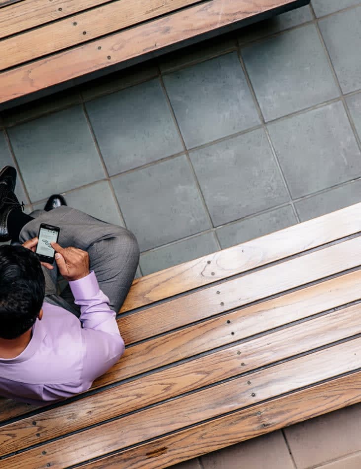 An overhead shot of a person in a purple shirt working on polished wooden benches