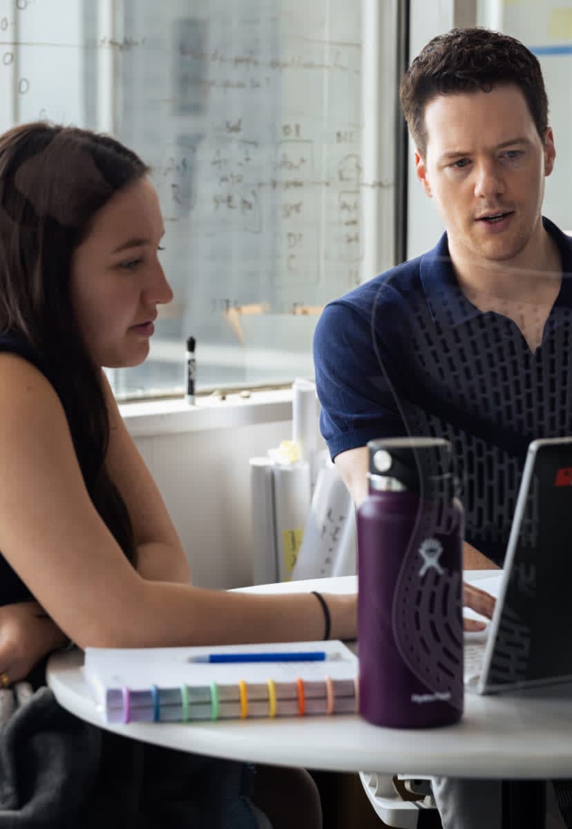 Two people in an office looking at a laptop screen